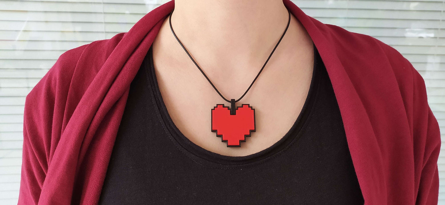 Person wearing a black shirt with a pixelated red heart necklace against a white background