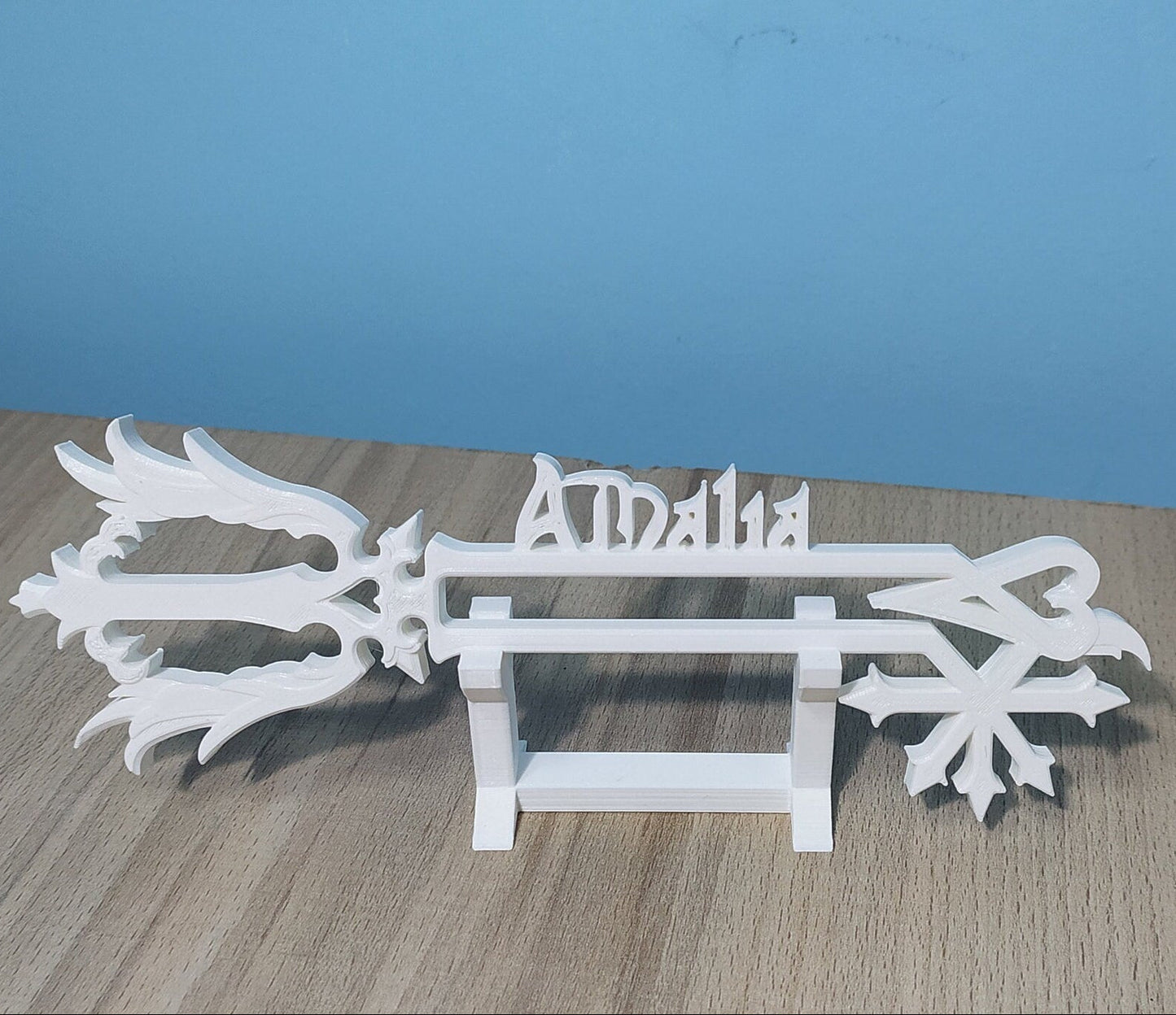 White decorative item with 'Amalia' branding on a wooden surface and blue background