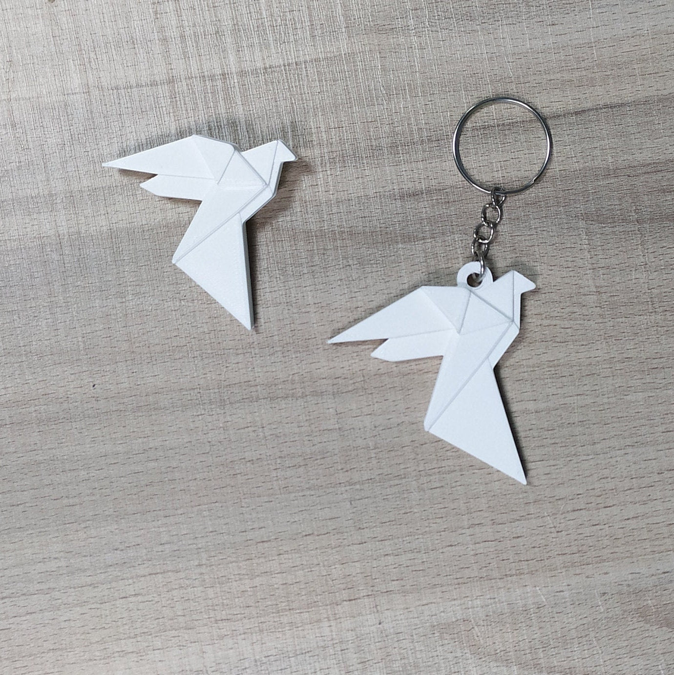 White origami-style keychain and earring on a gray surface