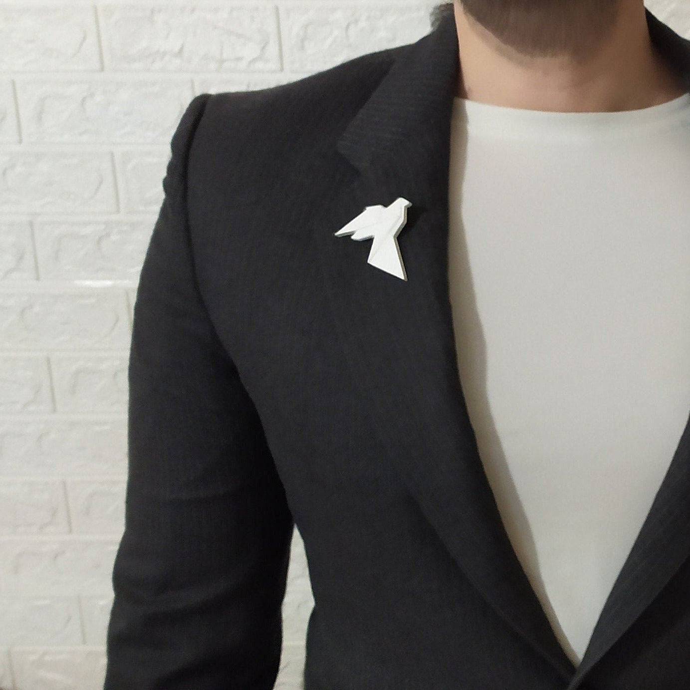White origami bird pin on a black suit jacket