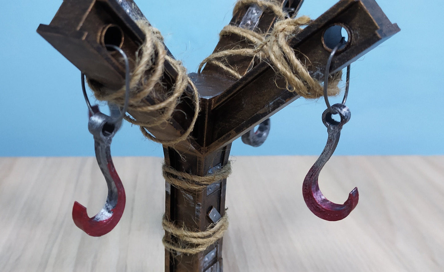 Metal bracket with hooks and twine on a wooden surface and blue background