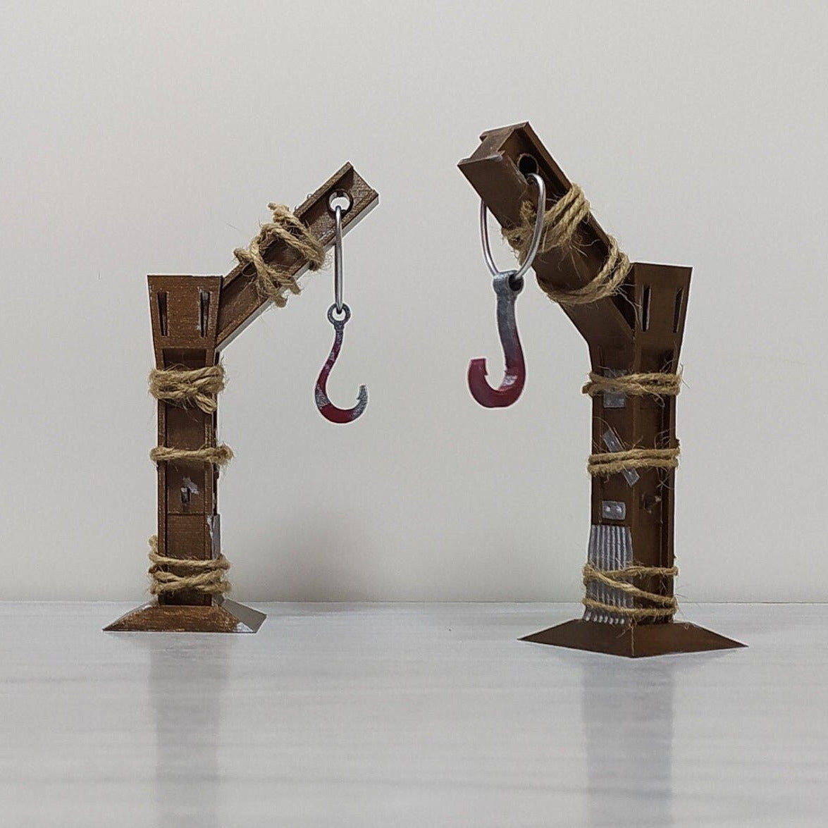 Two rusted metal armatures with hooks on a white background