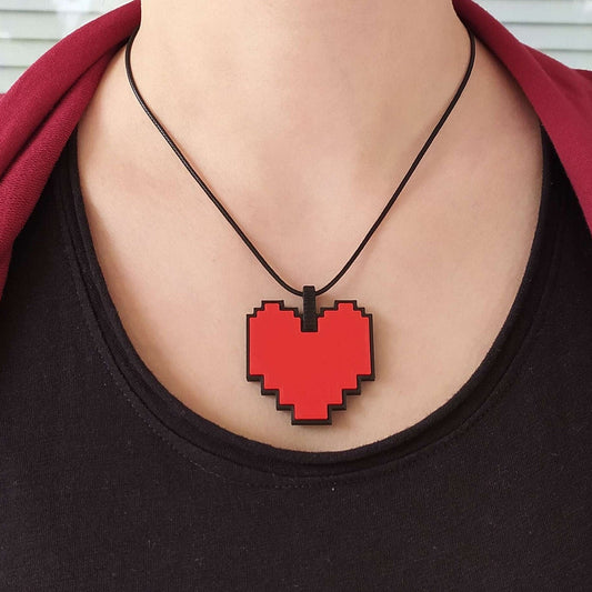 Person wearing a black shirt with a pixelated red heart necklace against a white background from Undertale