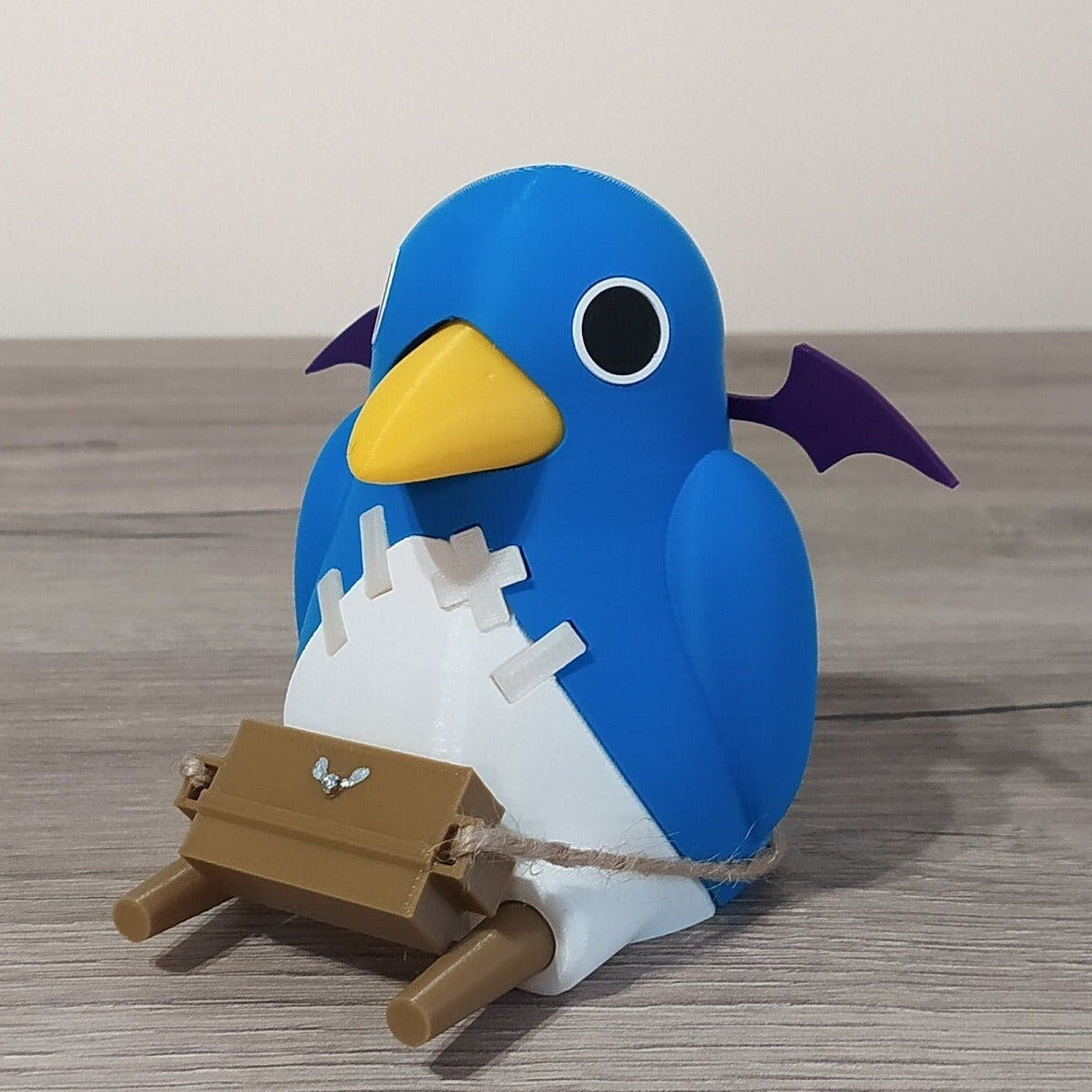 Blue penguin toy with a white chest and yellow beak on a wooden surface