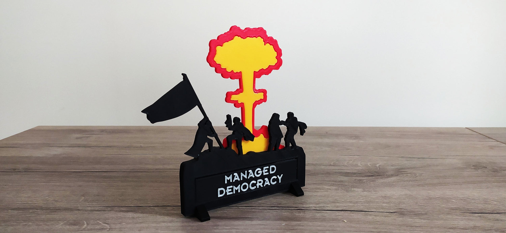 Model of a nuclear bomb with people and a flag on a wooden surface