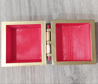 Gold jewelry box with red interior on a wooden surface