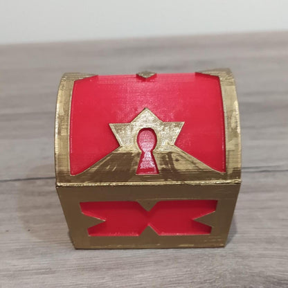 Red and gold treasure chest with a keyhole design on a wooden surface