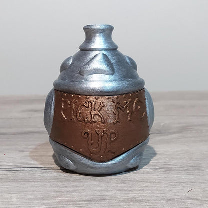 Metallic silver and brown container with 'Pick Me Up' text on a wooden surface