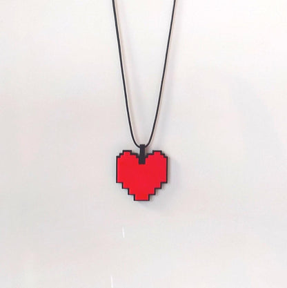 Pixelated red heart pendant on a black cord against a white background